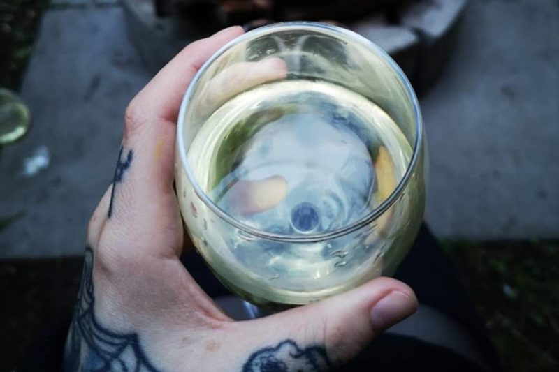A photo of a hand holding a glass of white wine.